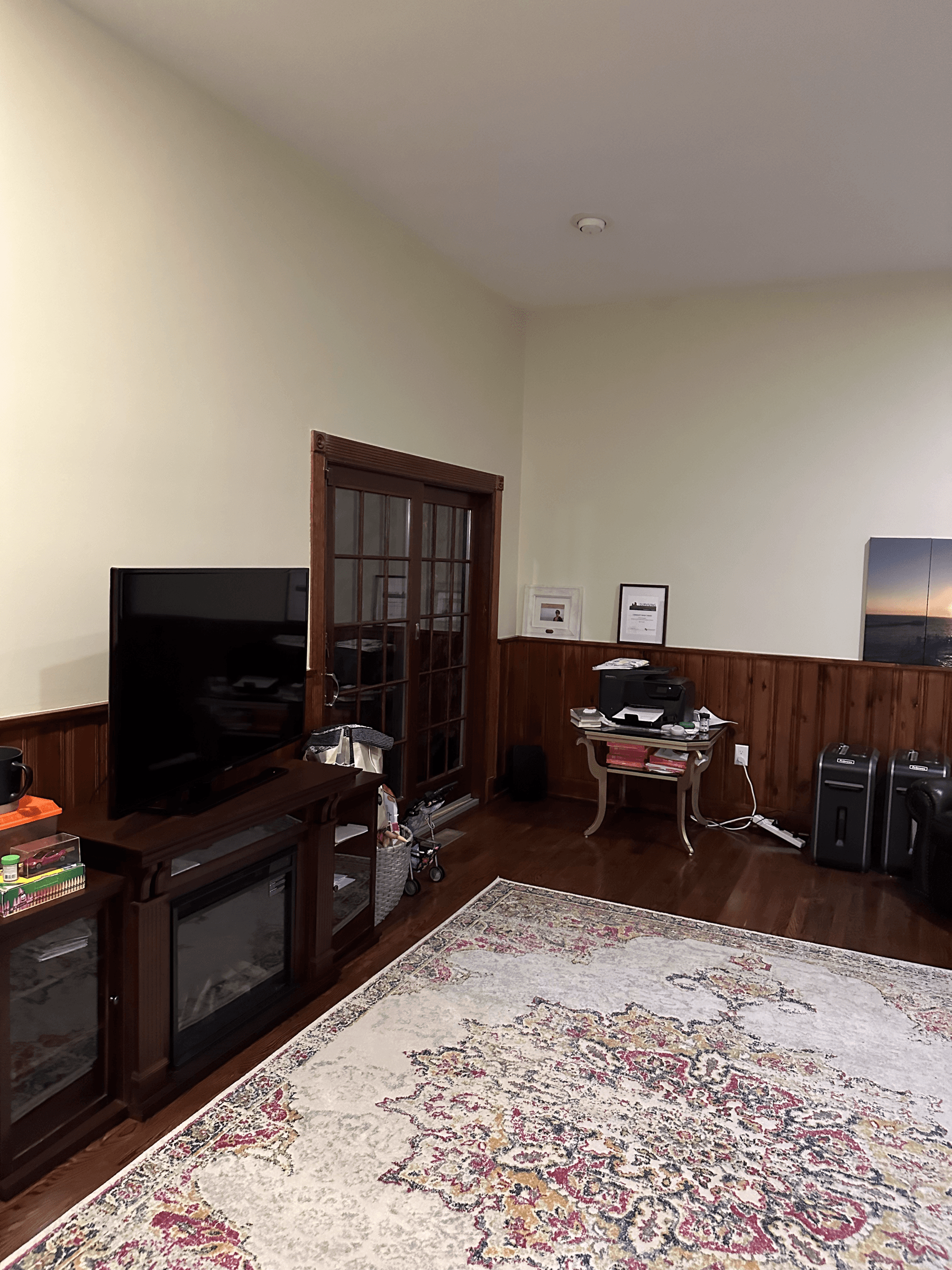 Family room corner with cream walls and wood French doors, before painting
