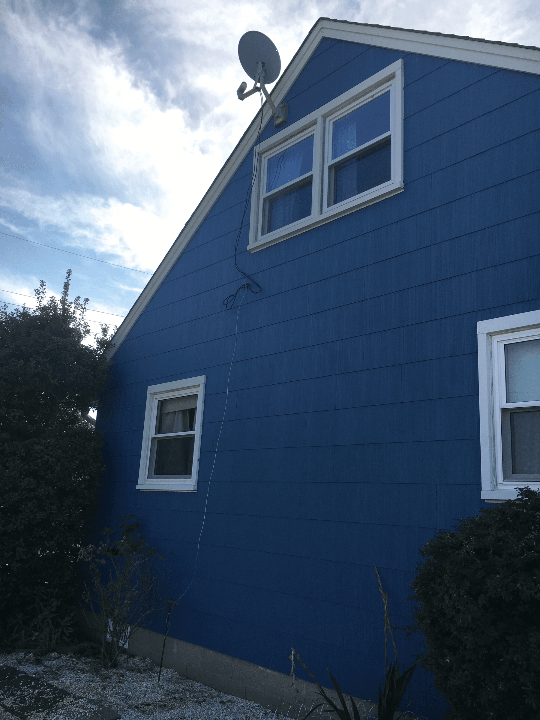 The same gable end painted blue with white window trim, after painting