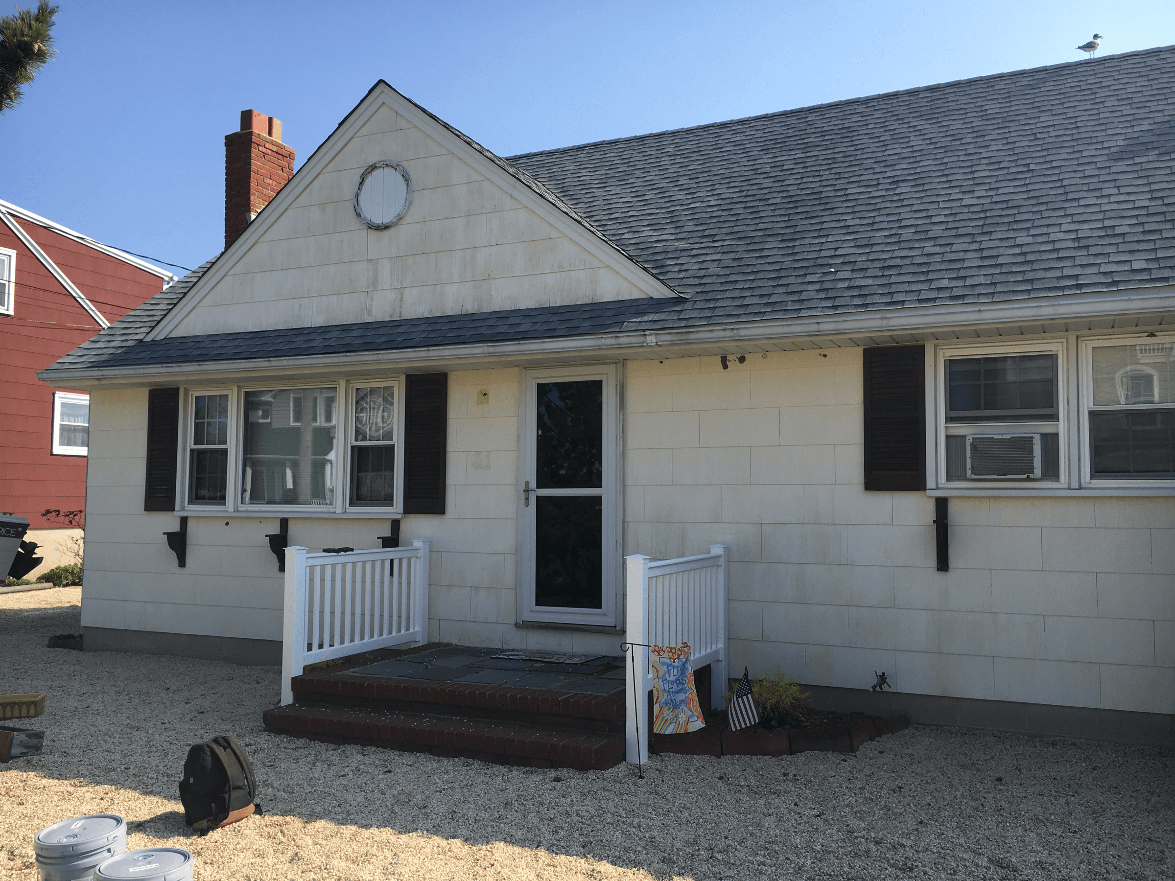 Back of a house with cream siding and dark shutters, before painting