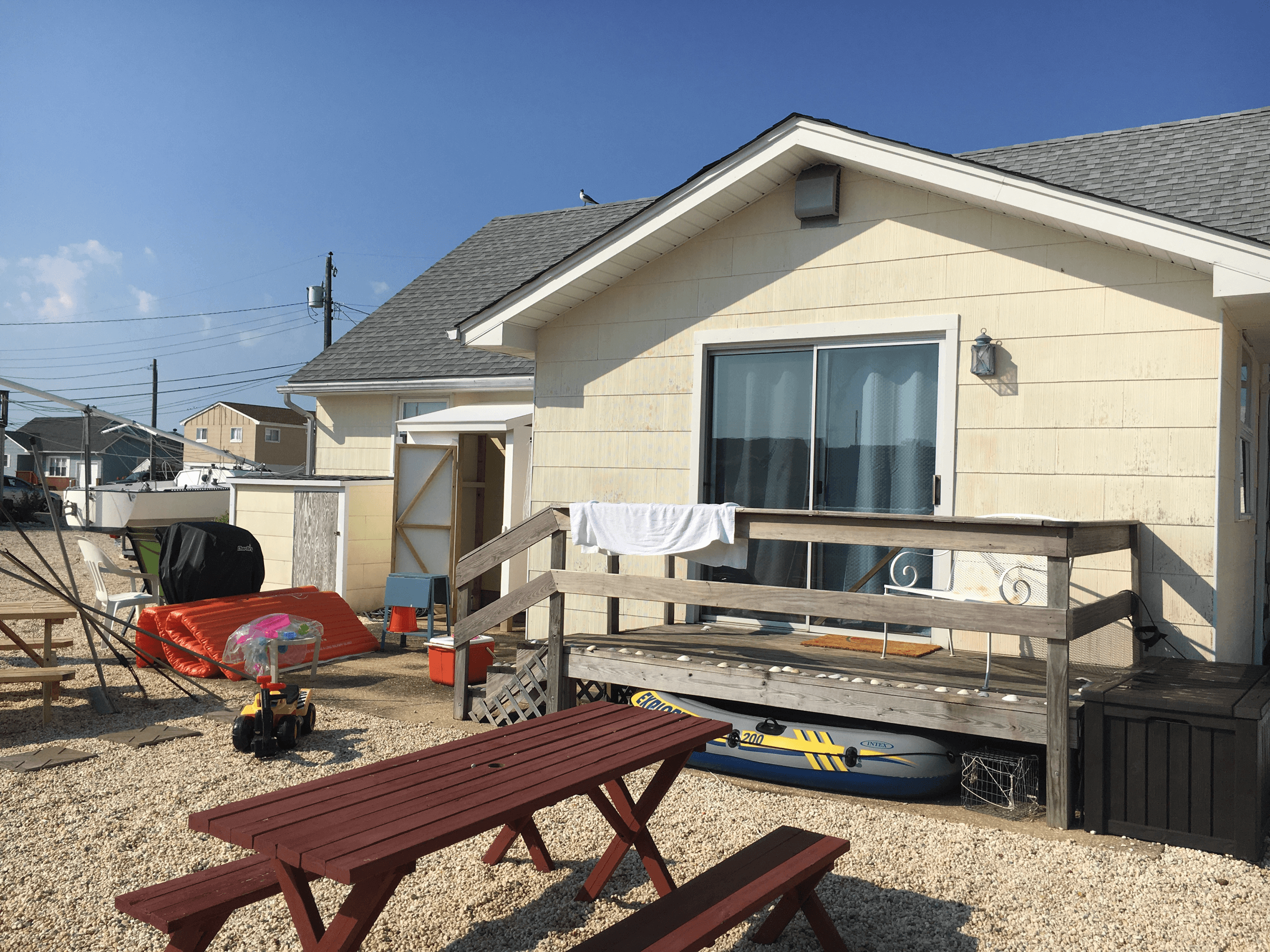 Rear of a house with cream siding and a wood deck, before painting
