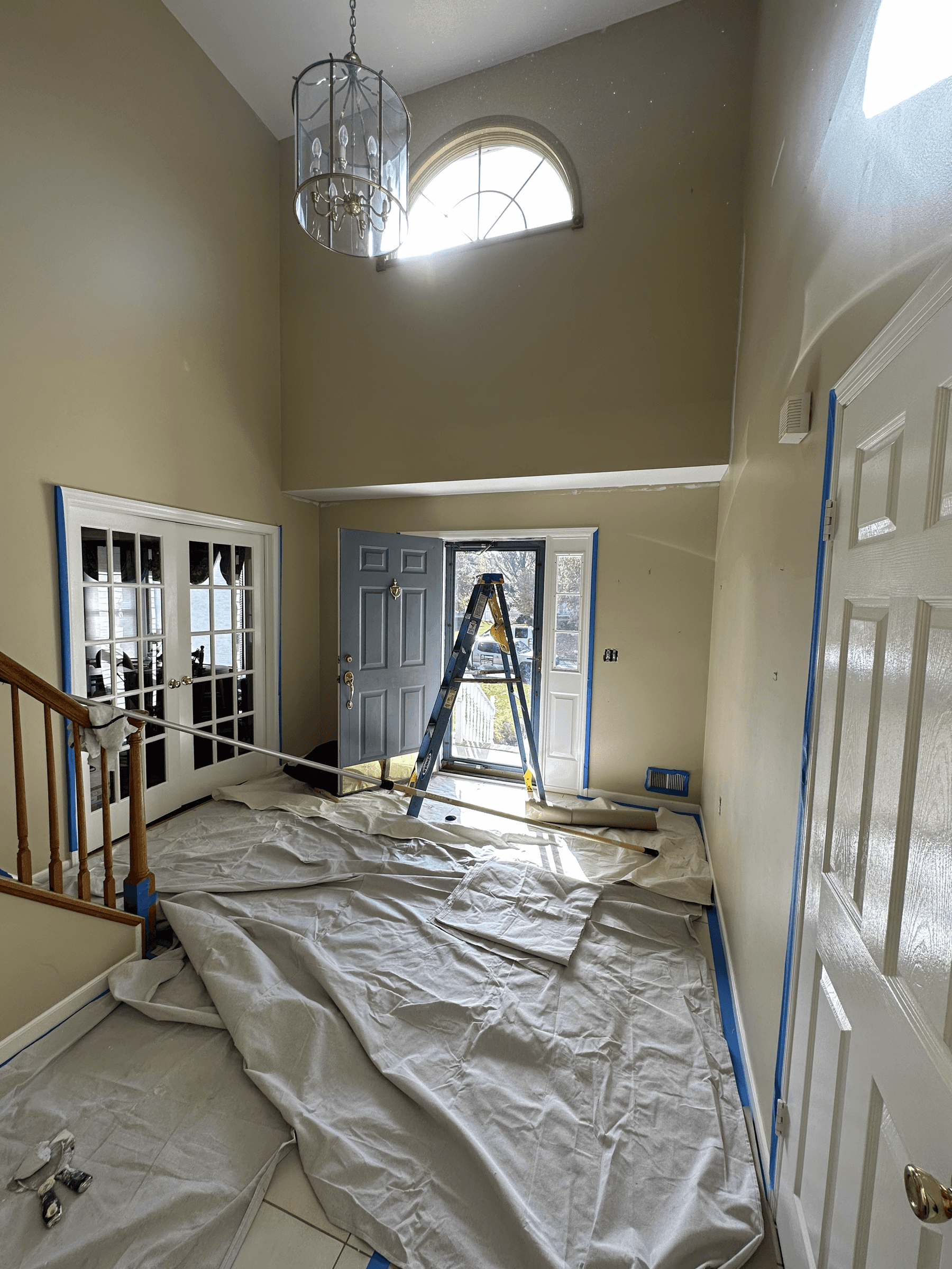 Foyer with the floor covered and the trim taped off before painting